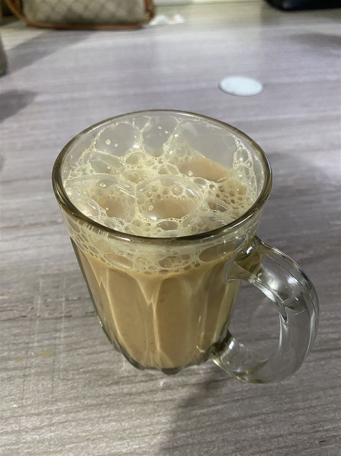 A glass mug of frothy teh tarik
